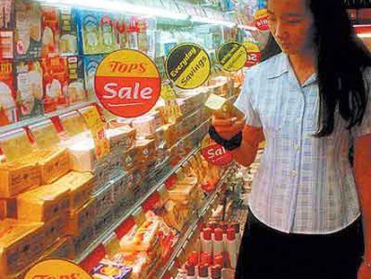 Una mujer mira las estanterías de mantequilla y lácteos en un supermercado de Bangkok.