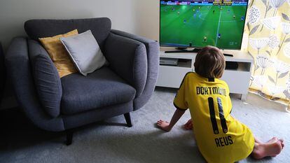 Un niño ve un partido de fútbol en la tele.