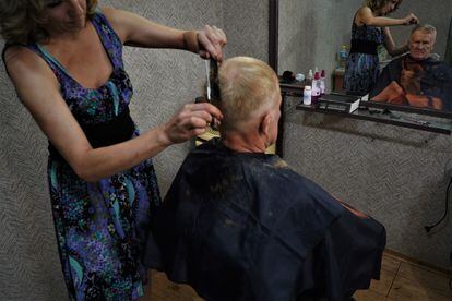 Tatiana corta el pelo a Oleksandr en su peluquería de Toretsk.