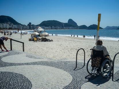 Una mujer en silla de ruedas, junto a las escaleras, mira la playa de Copacabana, en Río de Janeiro (Brasil).