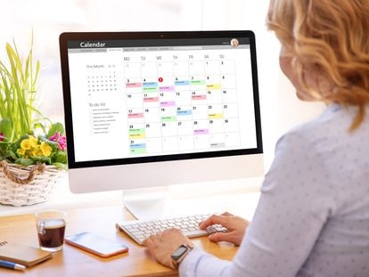 Una mujer utilizando una aplicación de calendario en un ordenador de sobremesa.