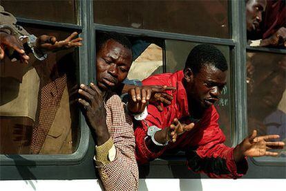 Un grupo de subsaharianos grita pidiendo agua desde el interior de un autobús que les conduce al sur de Marruecos.