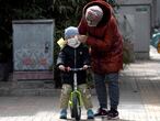 A woman wipes the face of a child on the streets of Beijing on Thursday, March 12, 2020. For most people, the new coronavirus causes only mild or moderate symptoms. For some it can cause more severe illness, especially in older adults and people with existing health problems. (AP Photo/Ng Han Guan)