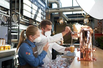 Two hoteliers serve beer to some customers in their premises.
