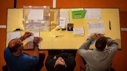 Los componentes de una mesa electoral esperan a que los ciudadanos voten en la Escola Grèvol (Barcelona).