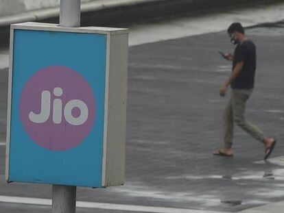 Un joven pasa junto a cartel de la empresa Jio, en la India. t