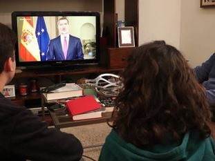 Una familia sevillana sigue el discurso de Felipe VI este miércoles.