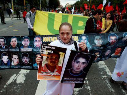 Una mujer sostiene dos fotografías de desaparecidos durante una marcha por las calles del centro de Bogotá (Colombia).