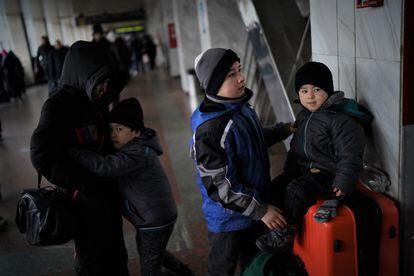 Islam, 12, in the center, looks after his brother Yasin, 4, while another brother, Illias, 7, hugs his mother, at the Kiev station.