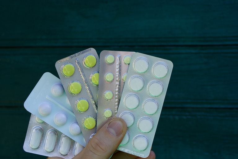 hand holds pills in packs on a green background