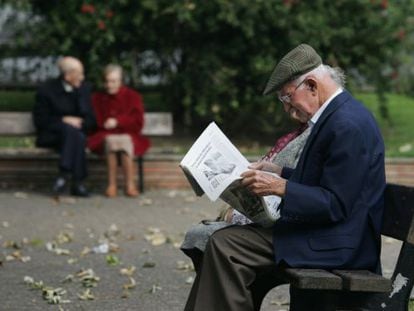 Un jubilado lee un peri&oacute;dico en un parque.