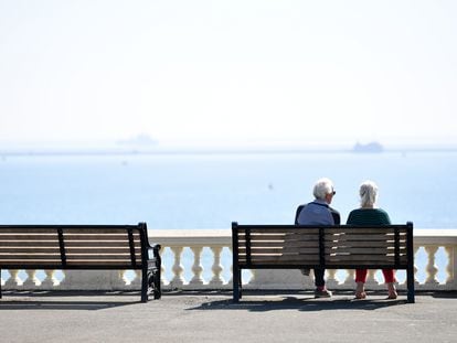 Una pareja de ancianos se sienta en un banco con vistas al mar en Plymouth, Inglaterra.