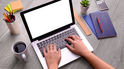 Woman hand using blank screen laptop computer on an office desk.