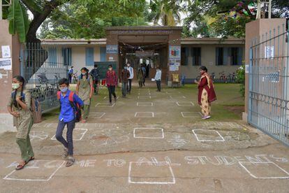 Una profesora observa la salida de los estudiantes de un colegio público de Bangalore, en India, el 23 de agosto de 2021, un día después de que en esta ciudad se haya permitido la apertura de centros educativos para alumnos de Secundaria después de un cierre que ha durado 18 meses.