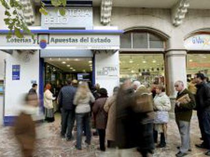 Varias personas esperan su turno fuera de una administraci&oacute;n de loter&iacute;a en Valencia.