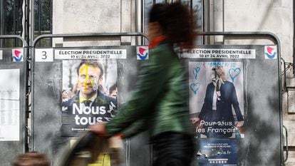 Una mujer pasaba el lunes junto a dos carteles electorales de Emmanuel Macron y Marine Le Pen, en París.