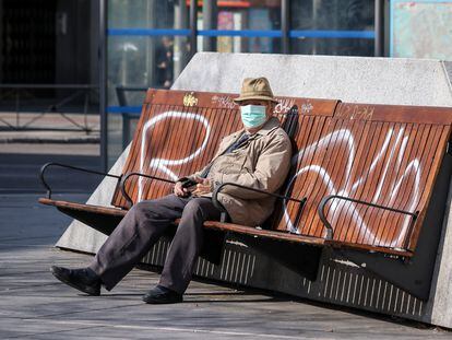 Un hombre con mascarilla sentado en un banco en Madrid.