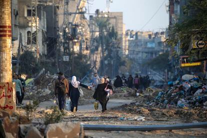 A group of people walk through collapsed buildings in the Al Maghazi refugee camp in central Gaza on January 19. 
