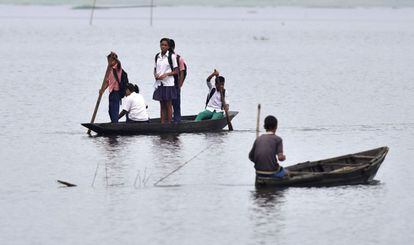 Niños indios van al colegio a bordo de barcas a través de las aguas producidas por las inundaciones en la localidad de Rajbari, en el estado de Assam (India).