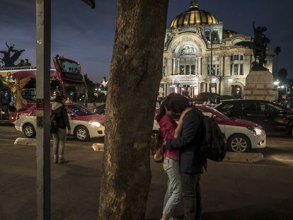 Una pareja se besa frente al Palacio de Bellas Artes en el centro histórico.