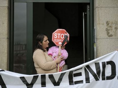 María del Pilar López sostiene a su hija Carolina, en el portal de su casa en Ourense. La plataforma Stop Desahucios logró frenar su desalojo por impago del alquiler.