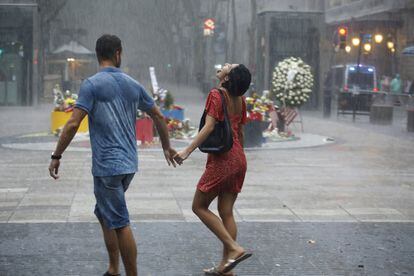 Una parella camina sota la pluja el dia del primer aniversari dels atemptats del 17-A a Barcelona.