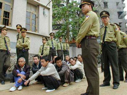 Policías chinos vigilan a traficantes de droga momentos antes de celebrarse el juicio que condenó a muerte a cinco de ellos en abril de 2001.