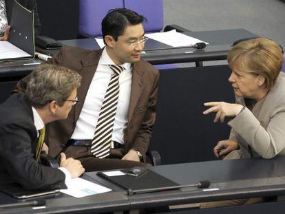 La canciller alemana, Angela Merkel, conversa con el ministro alemán de Exteriores, Guido Westerwelle (izda), y el ministro alemán de Economía, Phillip Rösler (centro), durante una sesión parlamentaria en Berlín.