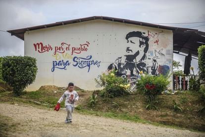 A boy runs next to a mural in La Fila, in the municipality of Icononzo.