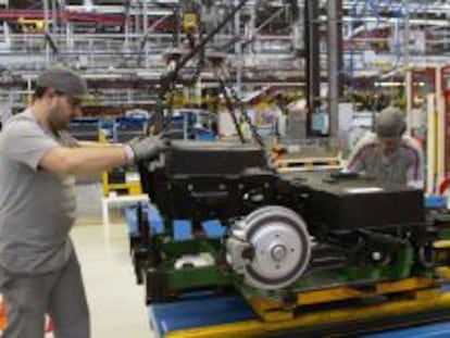 Dos operarios colocan las bater&iacute;as de una furgoneta el&eacute;ctrica Citro&euml;n Berlingo en la cadena de montaje de la planta de PSA. 