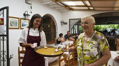 Rosa Devesa, a la derecha, sostiene un plato de arroz junto a su nieta Diana en su restaurante de D&eacute;nia.