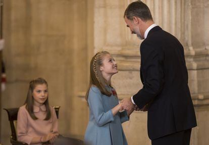 El Rey saluda a la princesa Leonor tras la imposición del Toisón de Oro en el Palacio Real mientras la infanta Sofía les observa al fondo.