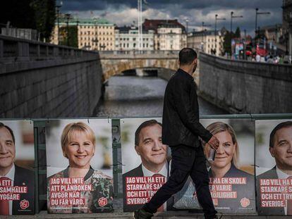 Un hombre camina junto a los carteles electorales de los ministros Stefan Loefven, Magdalena Andersson y Margot Wallstrom.