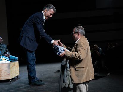 Rodrigo Londoño, ex comandante en jefe del estado mayor de las extintas FARC, recibe un regalo de Juan Manuel Santos, ex presidente de Colombia durante la tercera cumbre de la fundación Compaz, en Bogotá, el 14 de diciembre de 2022.