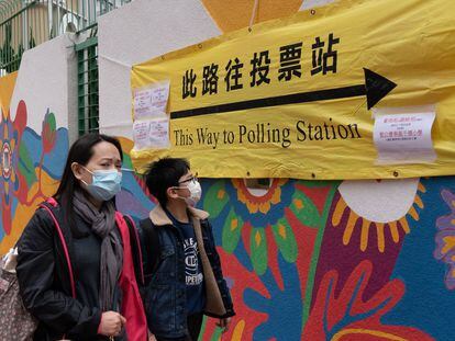 Una mujer acude a votar con su hijo en un centro electoral de Hong Kong, este domingo.