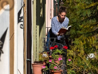 Una chica lee un libro en el balcón de su casa, durante el confinamiento en Barcelona.