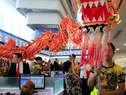 Operadores observan el desfile de un dragón tradicional en la Bolsa de Manila (Filipinas)