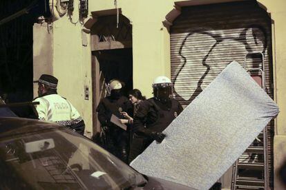 Un agente saca un colch&oacute;n de dentro de la casa ocupada en Vallcarca.