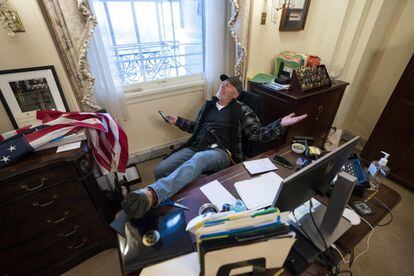 Un partidario del presidente de Estados Unidos, Donald J. Trump, se sienta en el escritorio de la presidenta de la Cámara de Representantes de Estados Unidos, Nancy Pelosi,