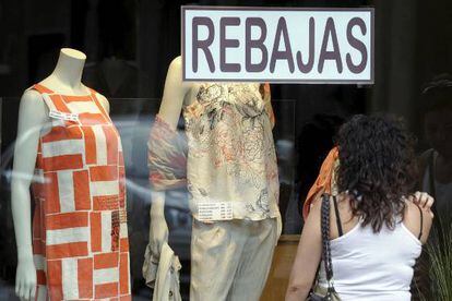 Una mujer mira un escaparate de una tienda en rebajas