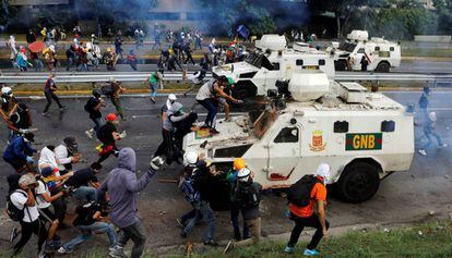 Varios manifestantes se enfrentan a un coche blindado de la policía durante una protesta en Caracas, el 1 de mayo de 2017.
