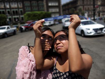 Jóvenes observan el eclipse solar en Ciudad de México.