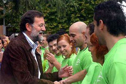 Rajoy saluda a un grupo de jóvenes de su partido vestidos con la camiseta de la nueva marca corporativa de Nuevas Generaciones.