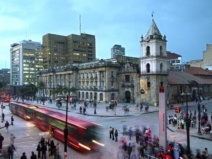 El palacio de San Francisco de Bogot&aacute;  con un autob&uacute;s pasando por delante y mucha gente transitando. 