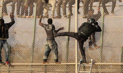 Un grupo de inmigrantes se enfrenta intenta sortear la valla de Melilla.