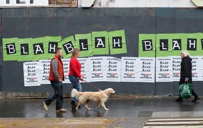 La gente pasa junto a carteles colocados por activistas climáticos antes de una marcha de protesta por las calles de Glasgow, Escocia, el viernes 5 de noviembre de 2021.