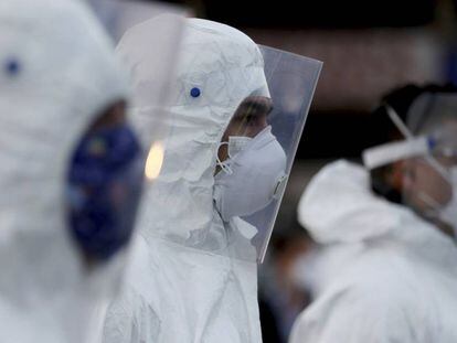 Varios trabajadores de un mercado colombiano llevan trajes y máscaras protectoras.