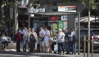 Ciutadans i turistes esperen en una de les parades del passeig de Gràcia per on passen busos que van al Park Güell.