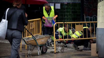 Unos obreros arreglan una calle de Sevilla, el lunes, durante su jornada laboral.