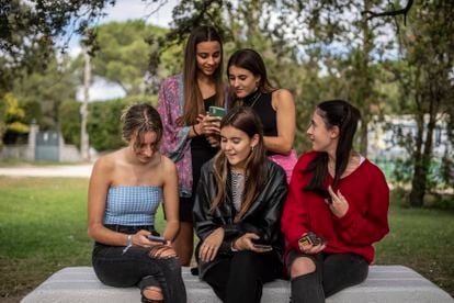 Las cinco amigas muestran sus teléfonos móviles y charlan sobre las publicaciones que ven en Instagram. 